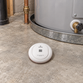 Kidde leak detector lying flat on the floor beside a water heater