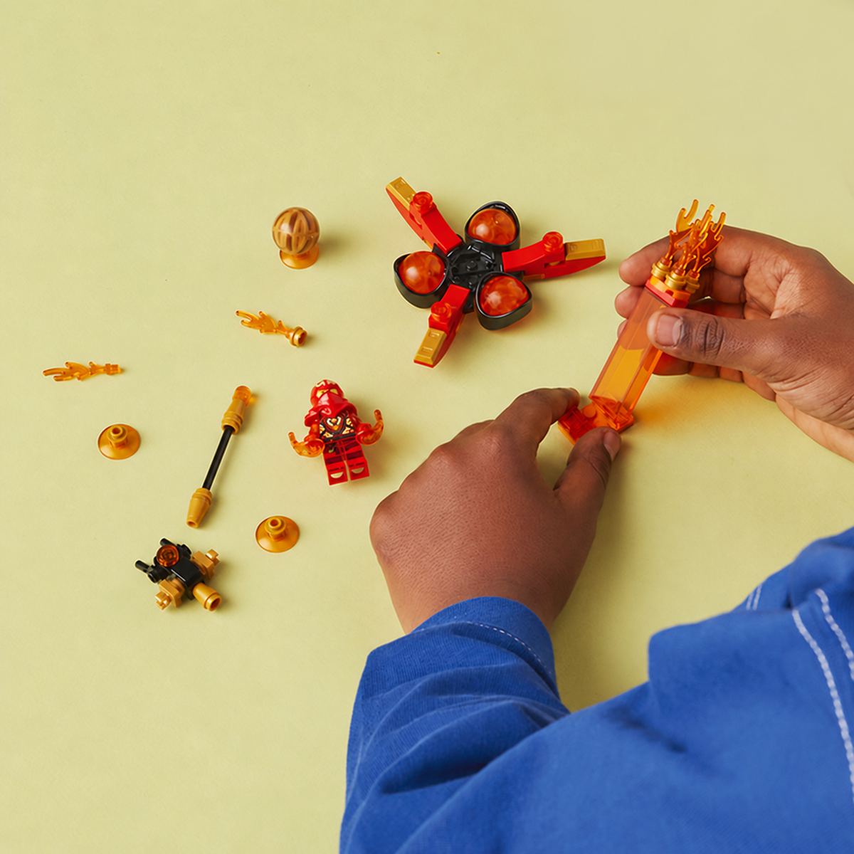 Child assembling the flaming holder from LEGO NINJAGO Kai's Dragon Power Spinjitzu Flip 71777.