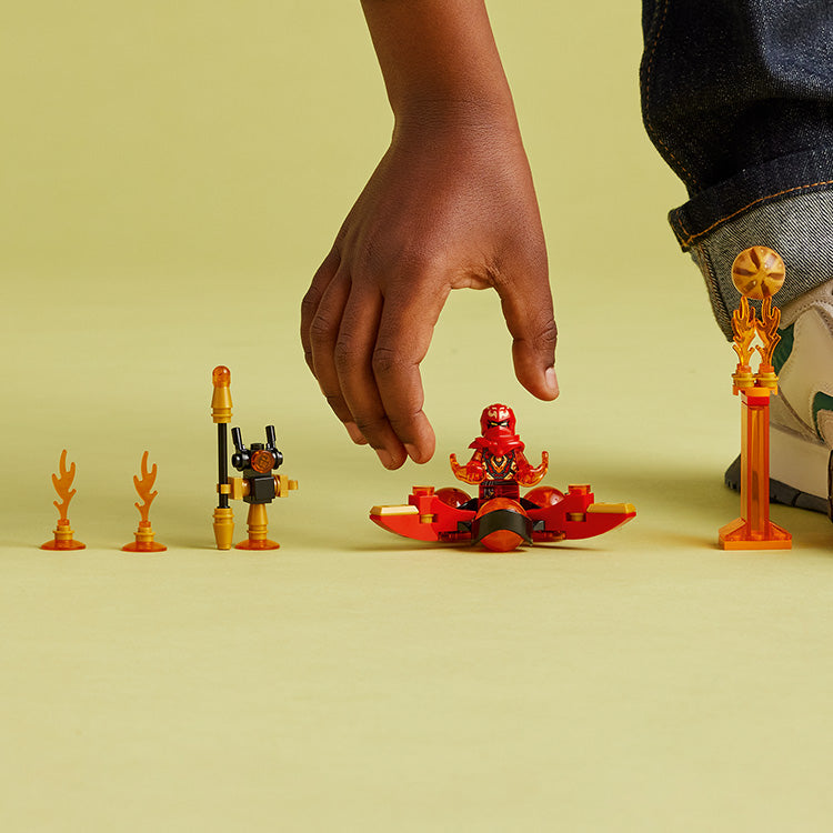 Child preparing LEGO NINJAGO Kai's Dragon Power Spinjitzu Flip 71777 with its spinner, droid and flame obstacles.