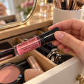 Choosing Pink Luster lip gloss from a vanity drawer