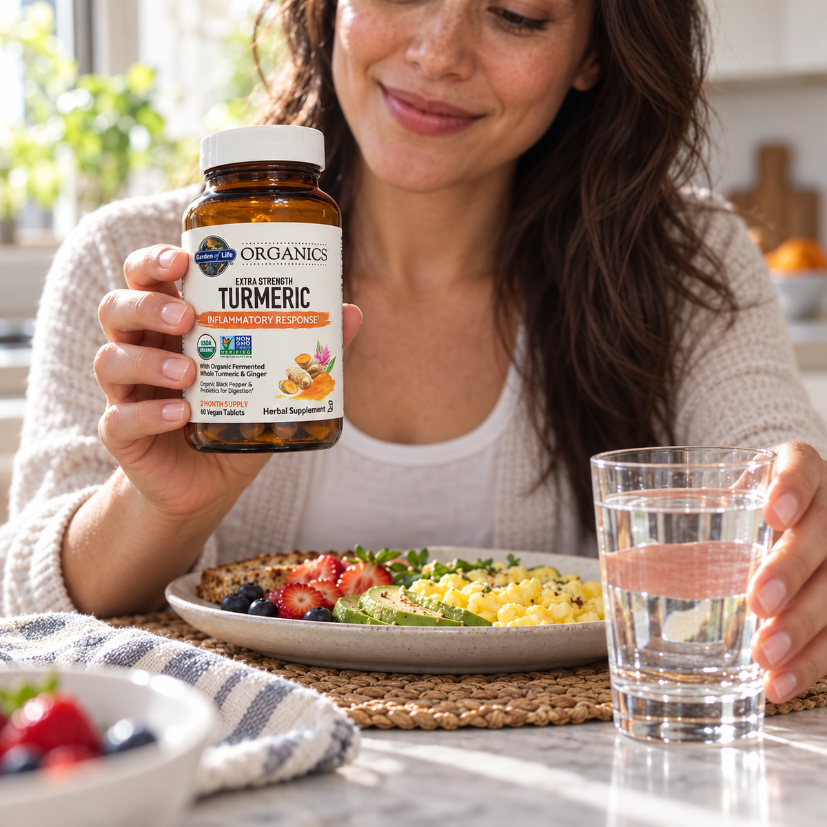 Holding Garden of Life Organics Turmeric beside breakfast