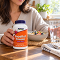 Holding NOW Inositol Powder beside breakfast