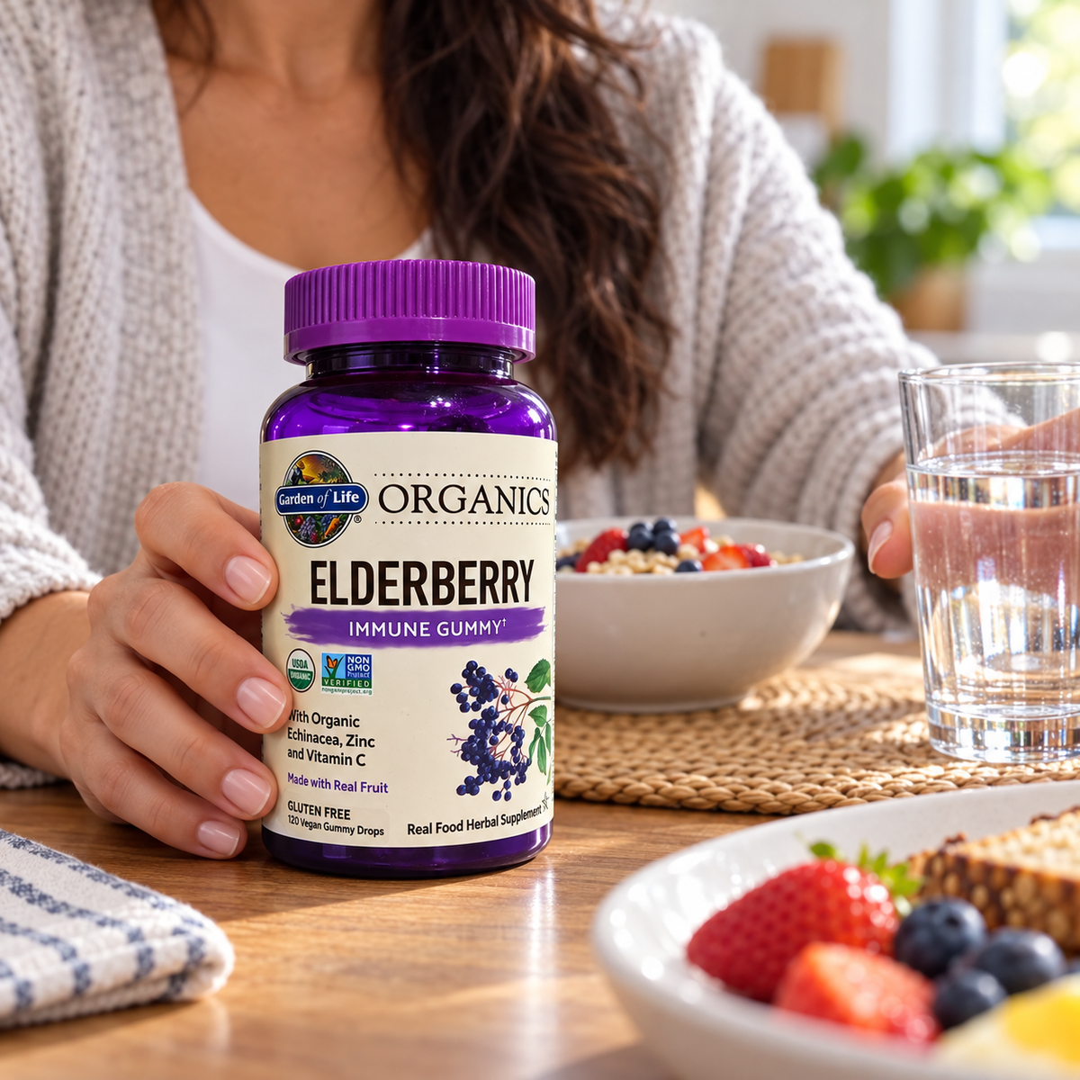Holding Garden of Life Organics Elderberry gummies beside breakfast