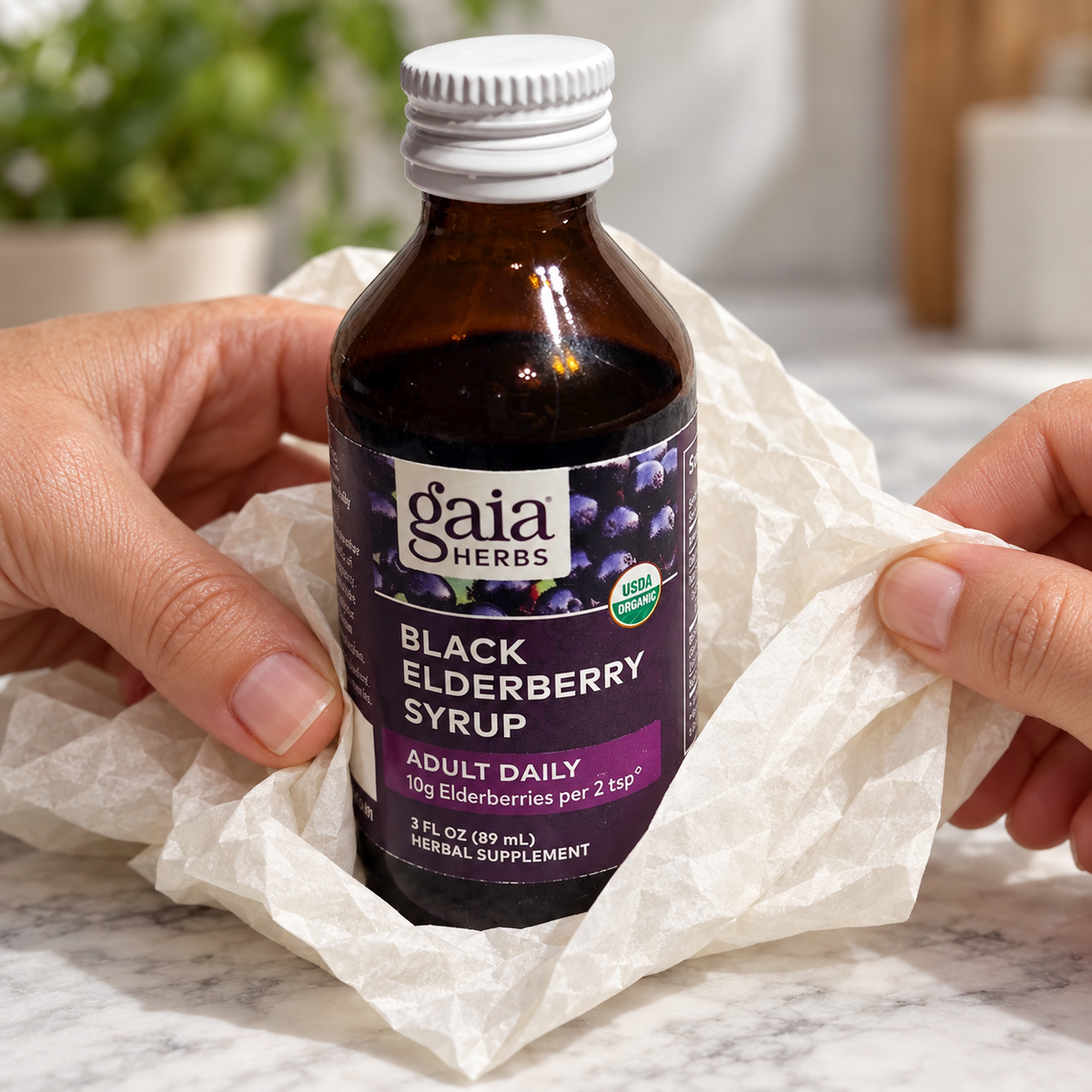 AI-generated gift-unwrapping illustration of adult hands removing ivory tissue from a Gaia Herbs Black Elderberry Syrup Adult Daily 3 fl oz bottle. White closure remains intact. Tissue is not included.