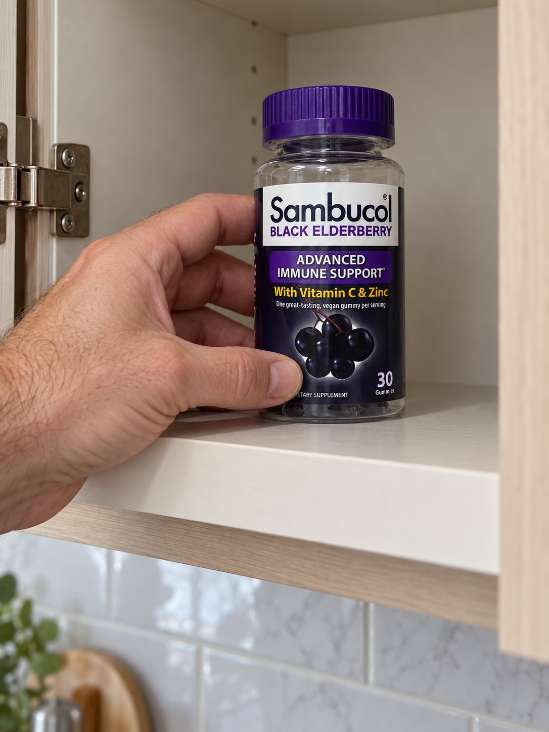 Returning a Sambucol Black Elderberry gummy bottle to a kitchen cupboard.
