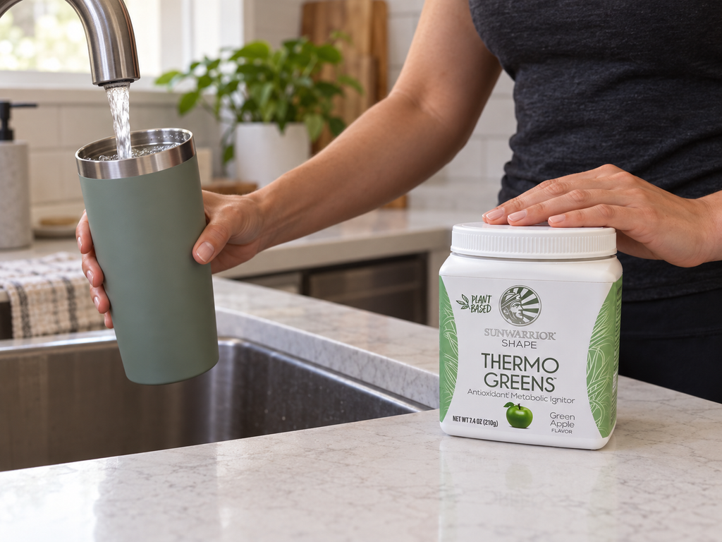 Filling a tumbler with water beside a Sunwarrior Thermo Greens tub.