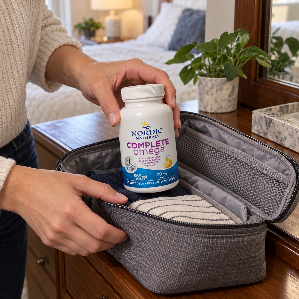 An adult packing a Nordic Naturals Complete Omega 60-soft-gel bottle in a fabric travel organizer