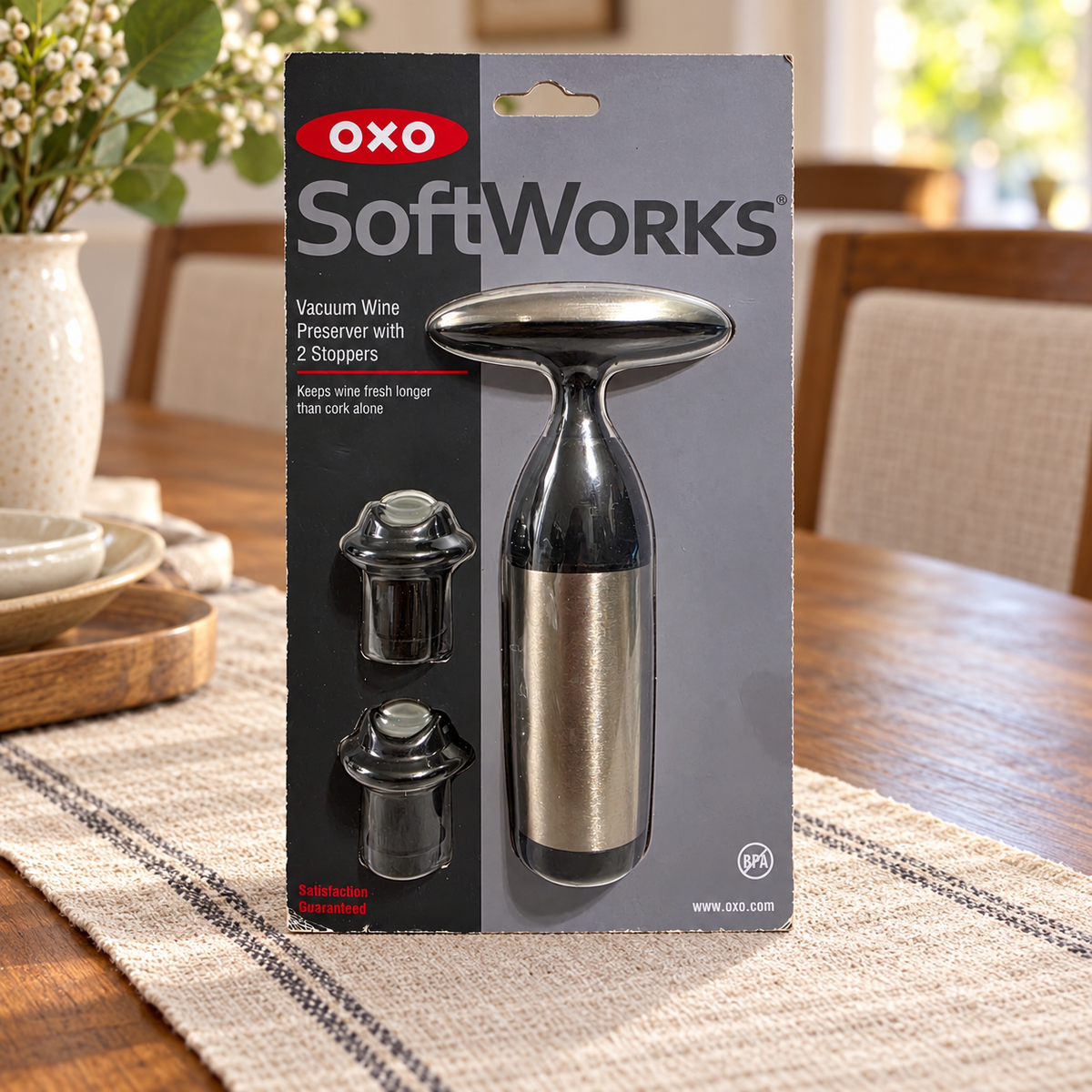 AI-generated lifestyle scene of one packaged OXO SoftWorks Vacuum Wine Preserver with two stoppers on a dining table. Props not included.