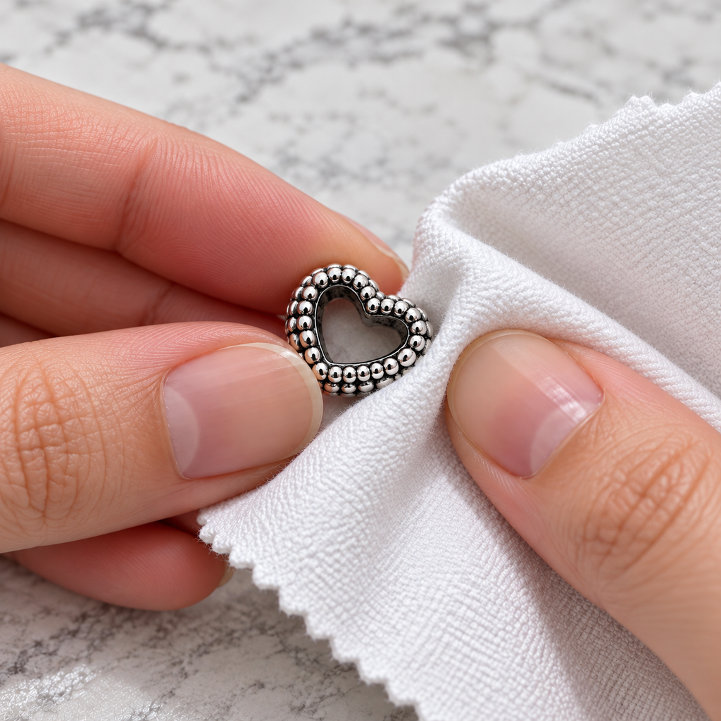 Small sterling silver heart charm being gently polished with a cloth