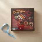 AI-generated background composite using the genuine stocked product photo. Gift-ready tabletop with an unmarked ribbon beside the package.