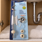Packaged EasyPOPUP ball rod assembly on a towel beside existing under-sink plumbing.