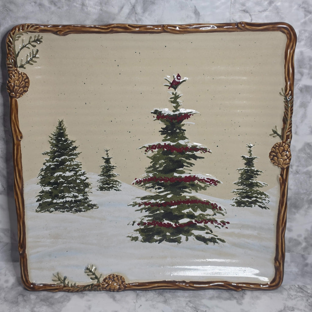 Snow Valley square dinner plate with a cardinal above snowy evergreen trees and raised pinecone border