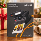 AI-generated lifestyle scene of one closed Polaroid Flip black instant camera retail box in a gift table setting. Props not included.