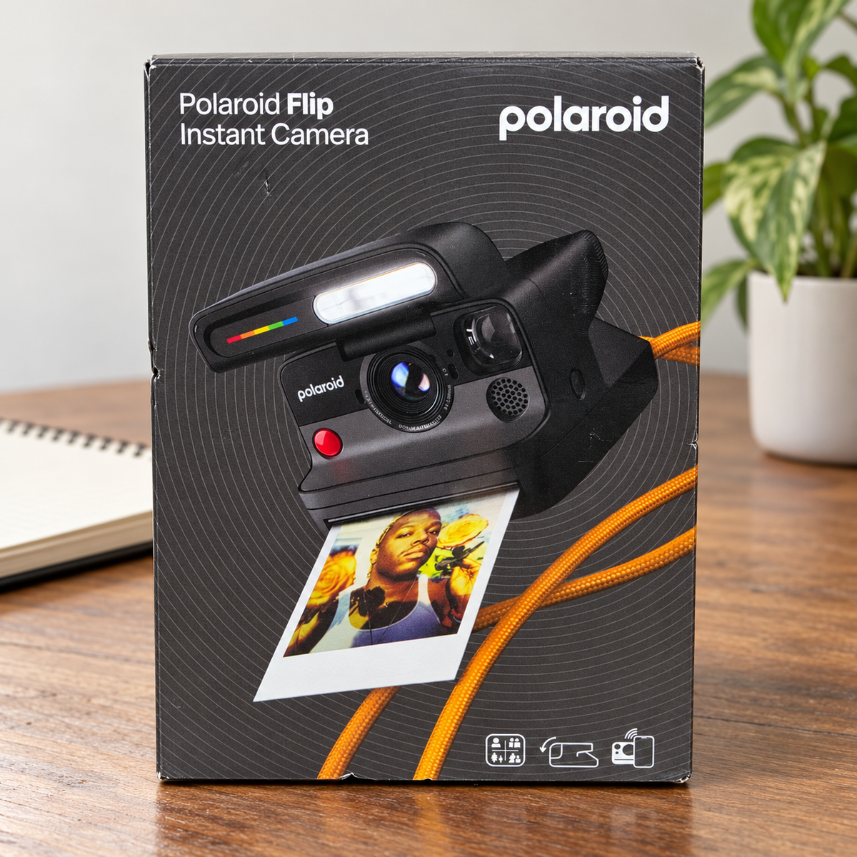 AI-generated lifestyle scene of one closed Polaroid Flip black instant camera retail box in a photography desk setting. Props not included.