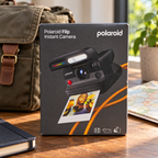 AI-generated lifestyle scene of one closed Polaroid Flip black instant camera retail box in a travel preparation setting. Props not included.
