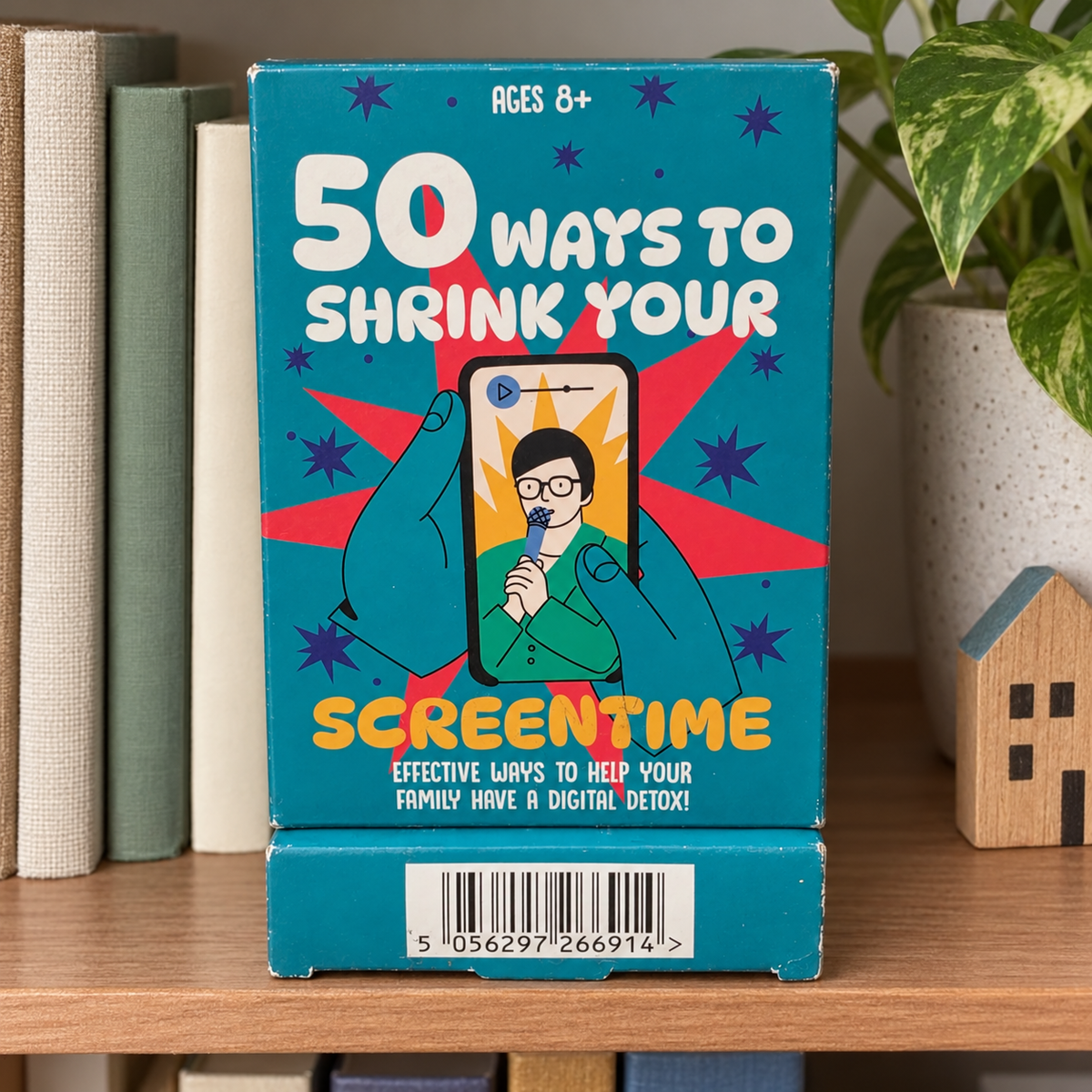 AI-generated lifestyle scene of the closed 50 Ways to Shrink Your Screentime package in a game shelf setting. Props not included.
