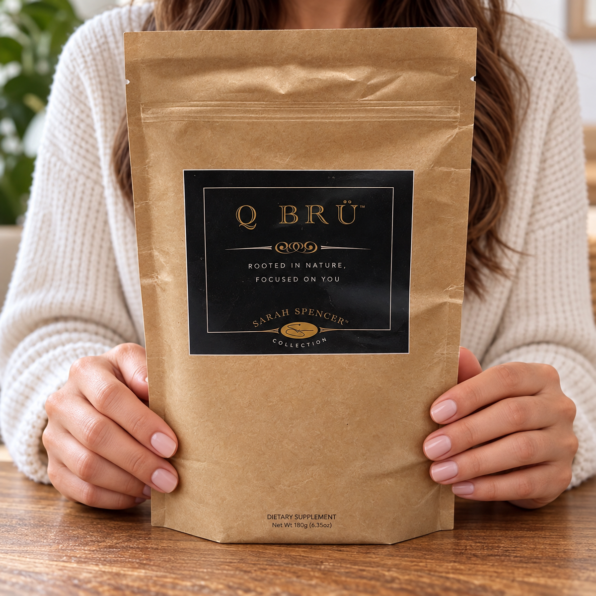 Adult holding the front-facing Q BRÜ Sarah Spencer Collection pouch