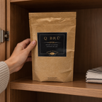 Q BRÜ pouch being placed on a shaded kitchen cabinet shelf