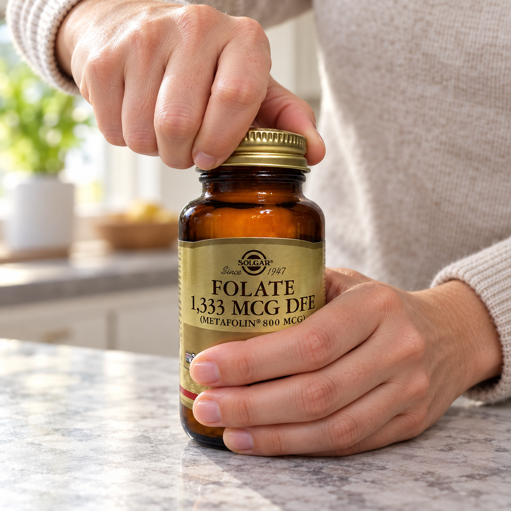 Adult twisting open the gold cap on a Solgar Folate bottle.
