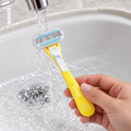 Adult rinsing a yellow Gillette Venus Tropical disposable razor under running water.