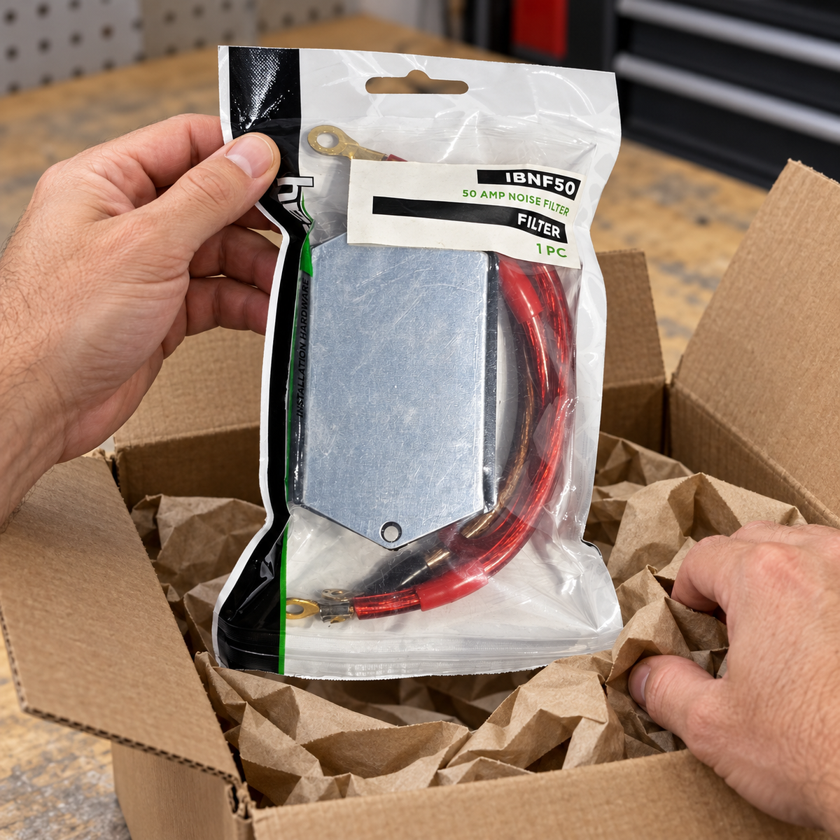 AI-generated lifestyle illustration of adult hands lifting the sealed Install Bay IBNF50 50 AMP noise-filter bag from a plain shipping carton.