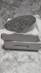 Actual round chrome-look shower head resting on its original foam packaging.
