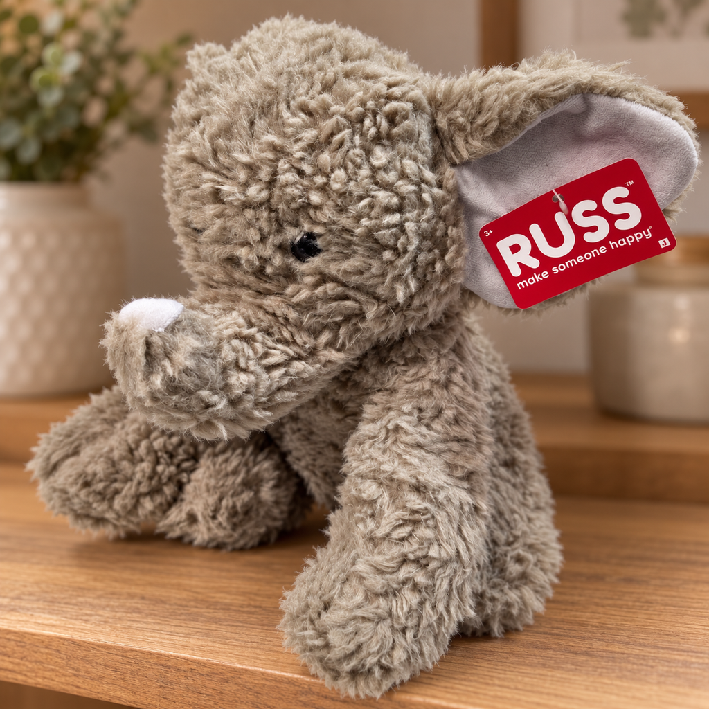 AI-generated lifestyle scene of the gray RUSS elephant plush with white trunk tip and attached red tag on a display shelf. Props not included.