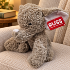 AI-generated lifestyle scene of the gray RUSS elephant plush with white trunk tip and attached red tag in a reading nook. Props not included.