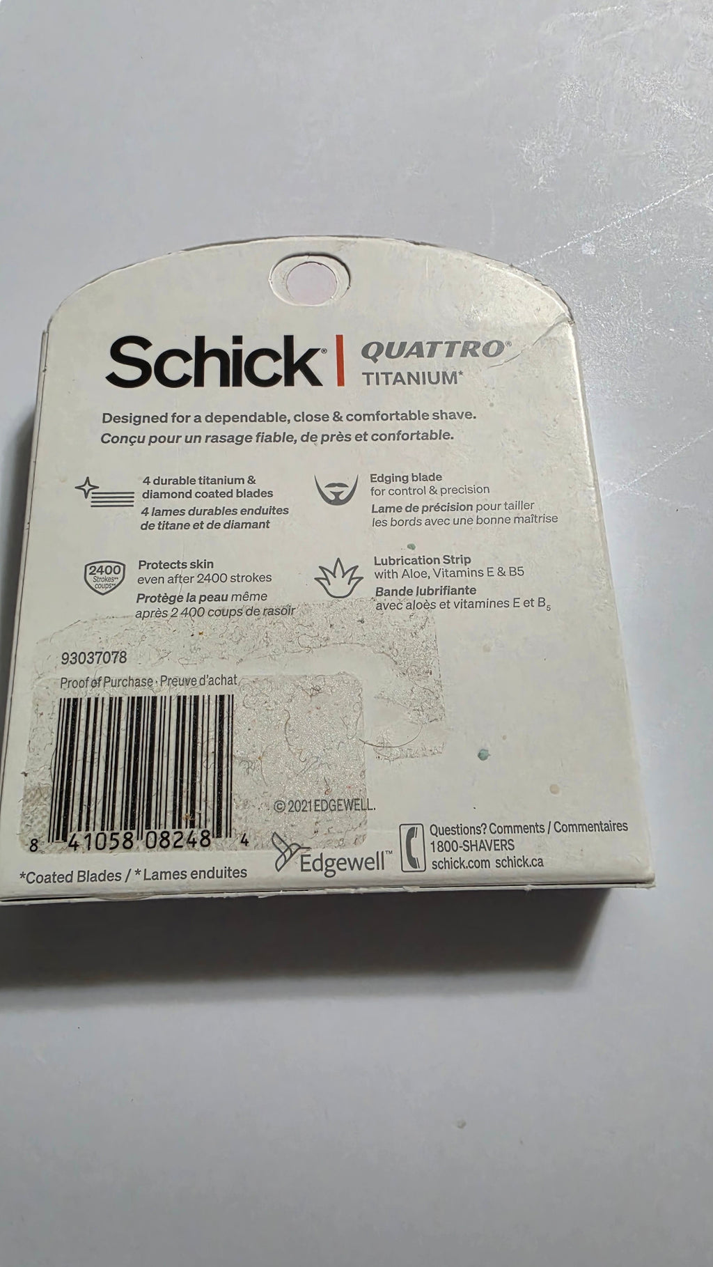 Back of the actual Schick Quattro Titanium six-cartridge box, with UPC 841058082484, product features, packaging scuffs and sticker residue
