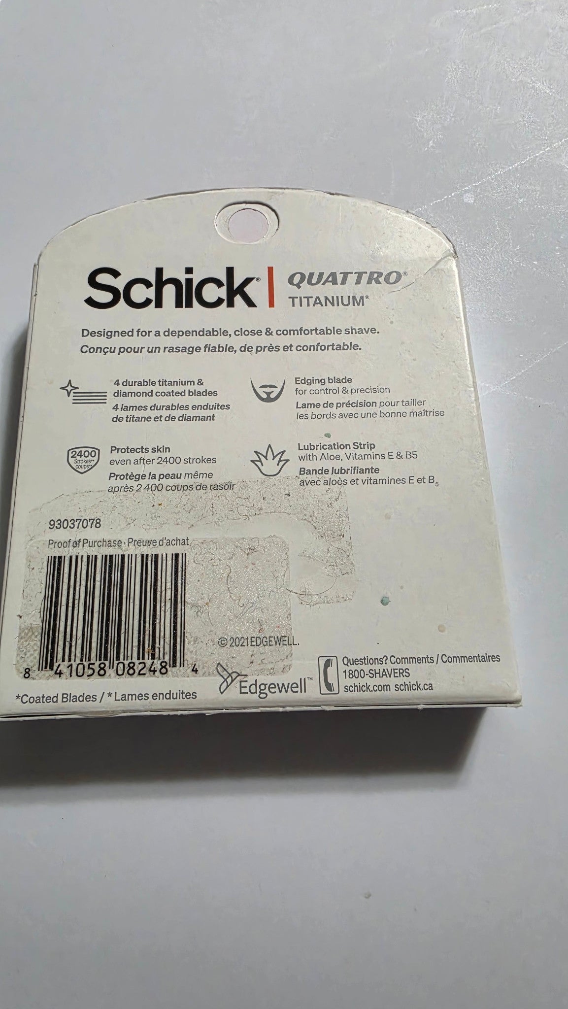 Back of the actual Schick Quattro Titanium six-cartridge box, with UPC 841058082484, product features, packaging scuffs and sticker residue