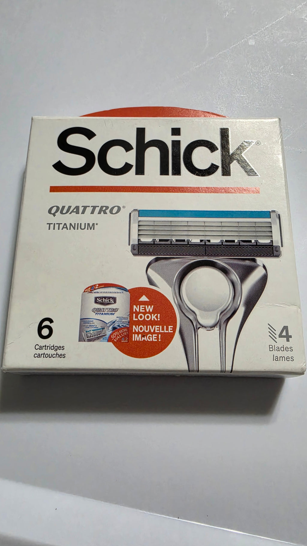 Actual stocked box of Schick Quattro Titanium razor blade refills, six cartridges, showing the front packaging and light edge wear