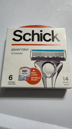 Actual stocked box of Schick Quattro Titanium razor blade refills, six cartridges, showing the front packaging and light edge wear