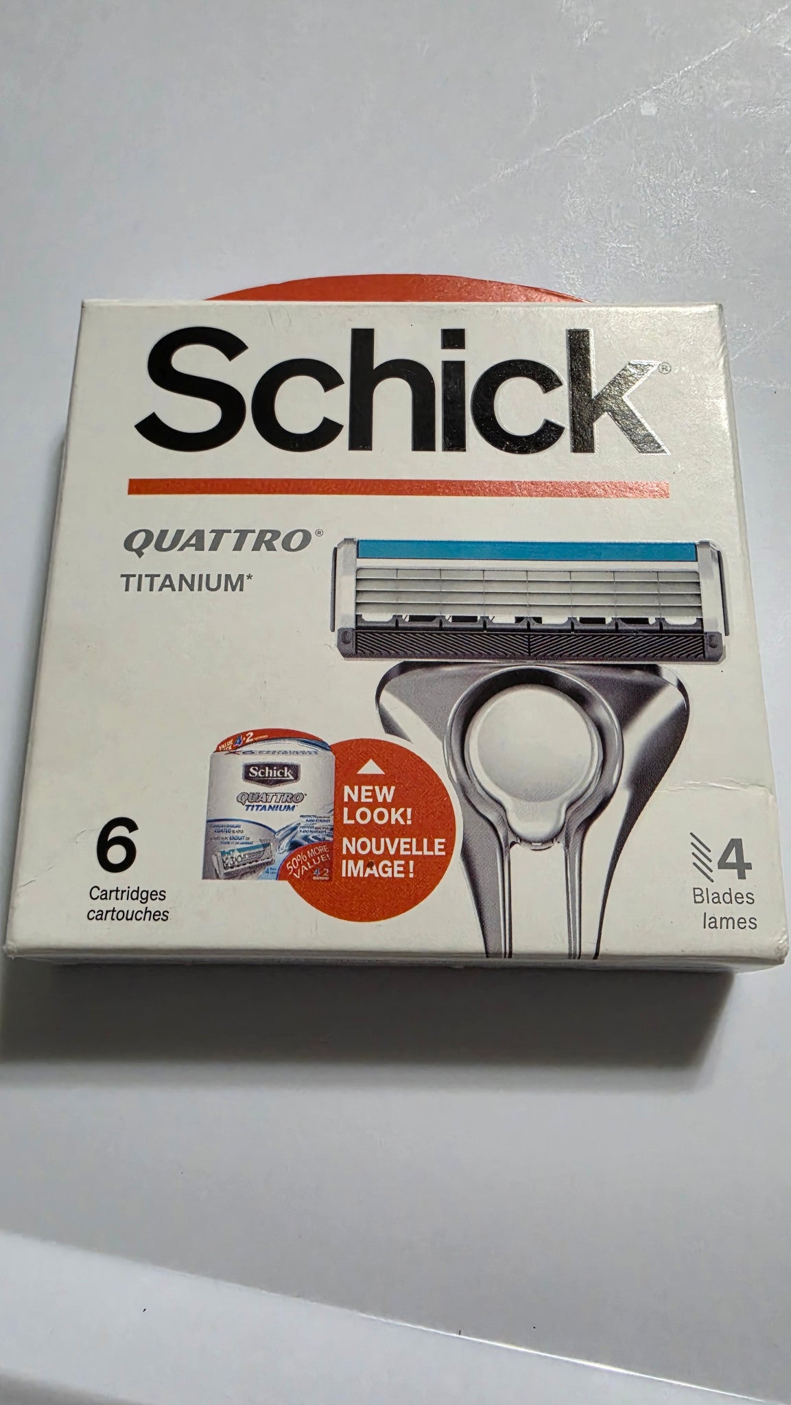 Actual stocked box of Schick Quattro Titanium razor blade refills, six cartridges, showing the front packaging and light edge wear