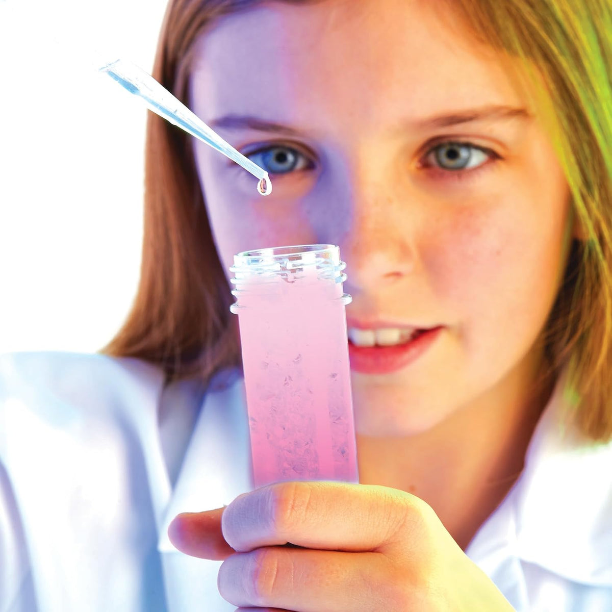 Close-up of a child using a pipette above an open test tube in a Scientific Explorer experiment demonstration.