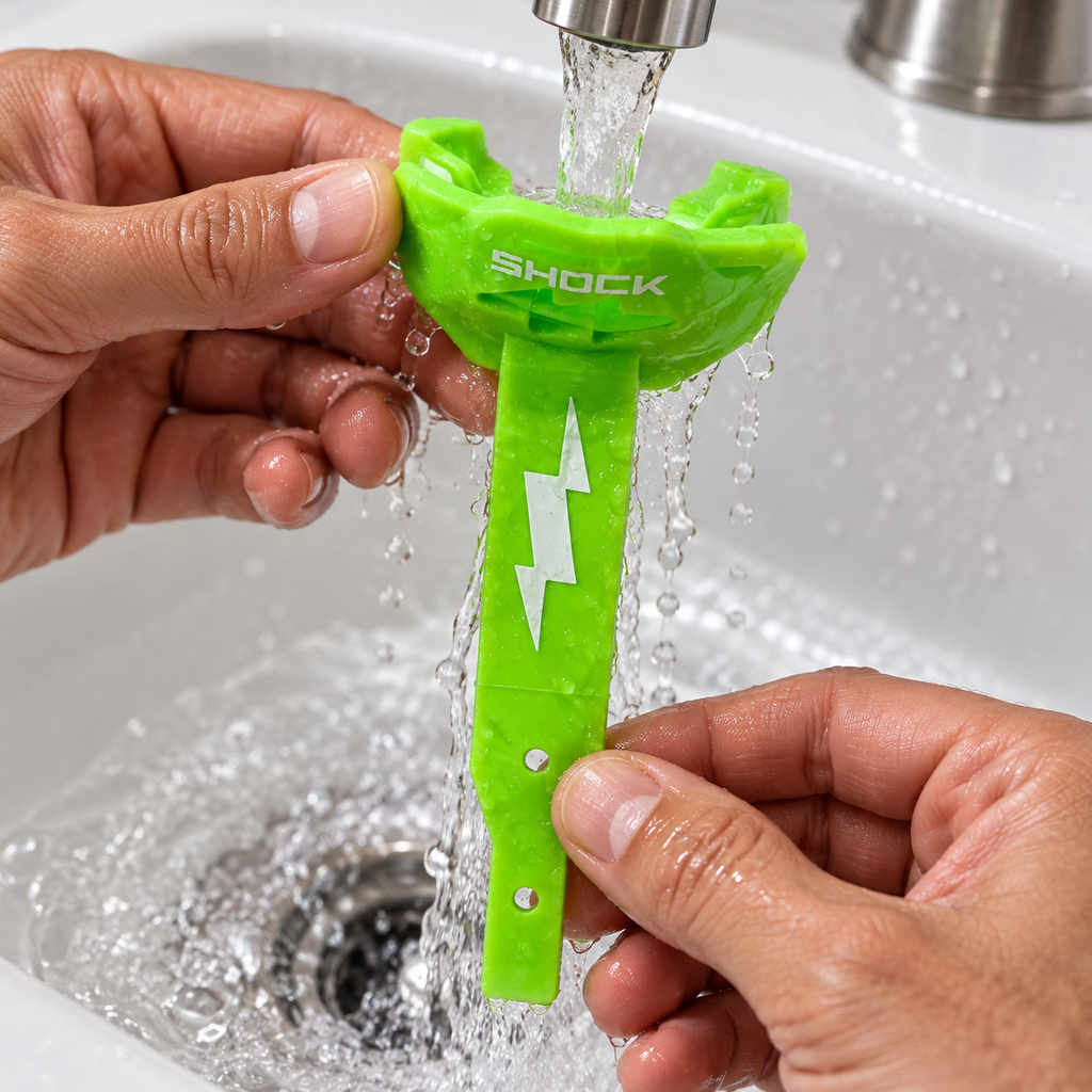Rinsing a green Shock Doctor Thunder Bolt lip guard after practice