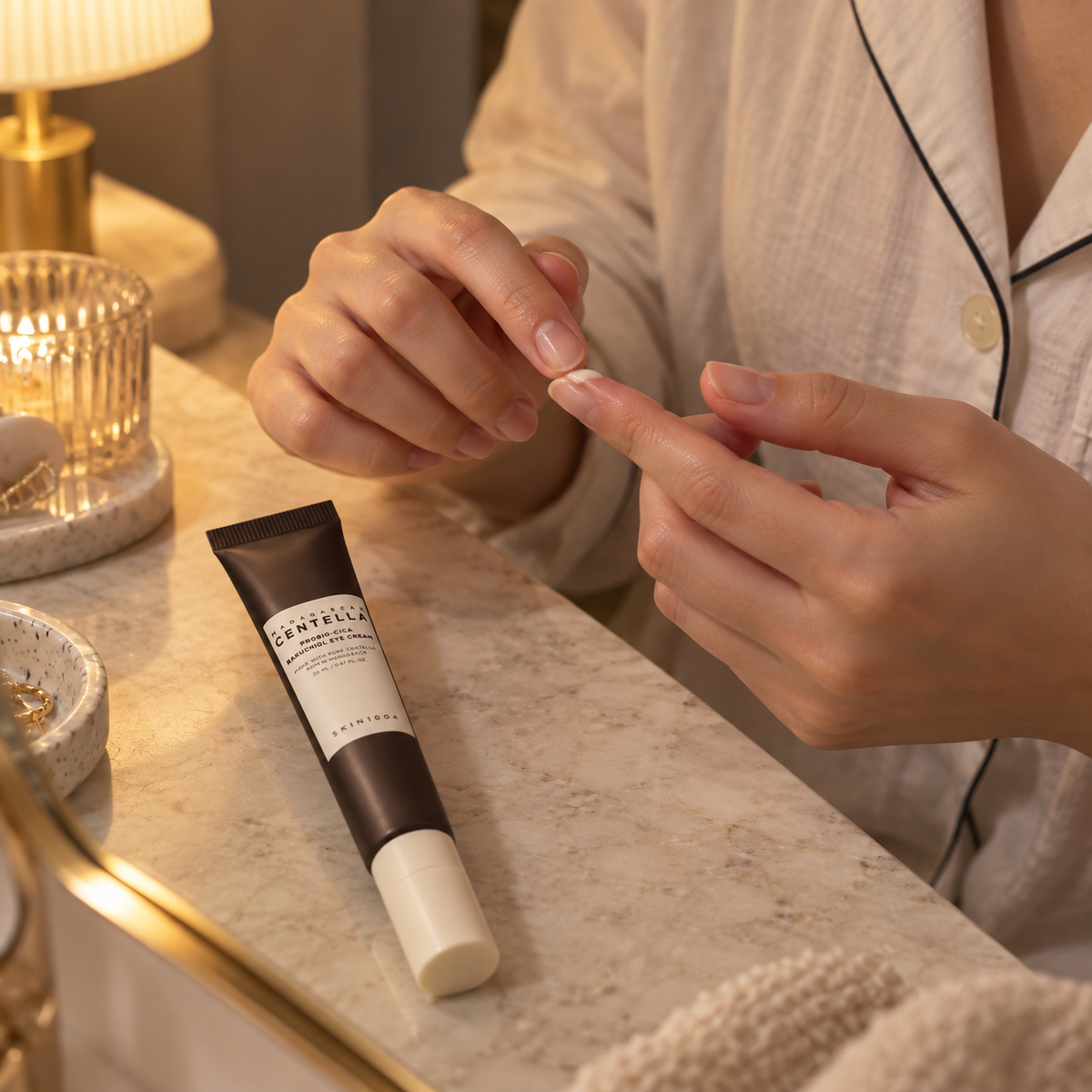 Small dab of eye cream on fingertips beside the SKIN1004 Bakuchiol Eye Cream tube