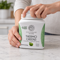Hands opening a Sunwarrior Shape Thermo Greens Green Apple tub.