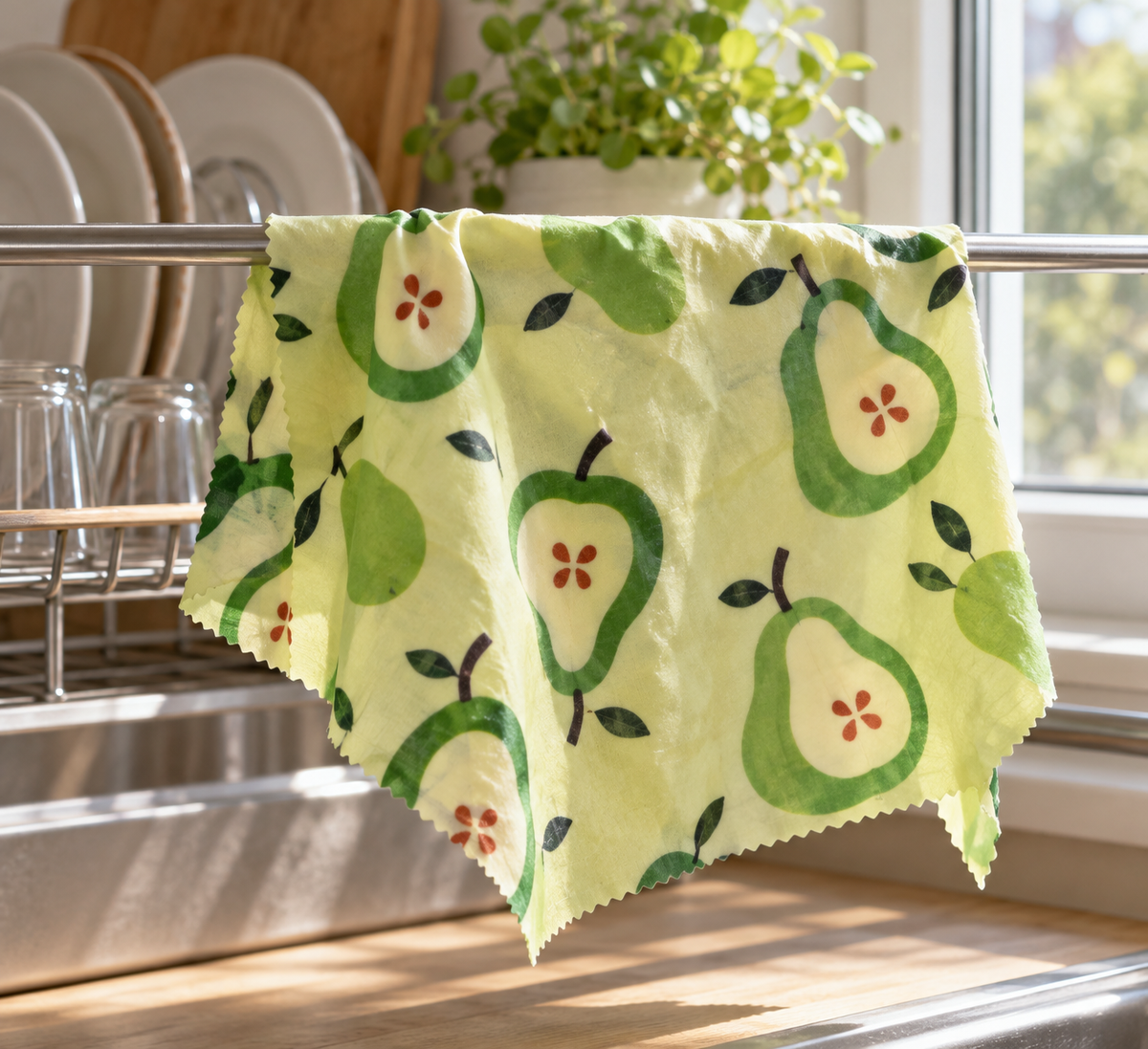 AI-generated lifestyle illustration: Single green pear-print SuperBee wrap air-drying on a rack; food and props not included.