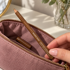 Mary Kay Tahitian Gold wooden eyeliner pencil being lifted from a mauve makeup pouch