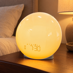Illustrative lifestyle scene of Trending Now sunrise clock on a walnut bedside cabinet in warm evening light