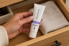 A hand selecting the closed UNBLEMISH Invisible Matte Defense tube from an indoor drawer