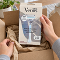 Adult hands unpack a closed Gillette Venus For Pubic Hair & Skin carton labeled one razor and two cartridges.
