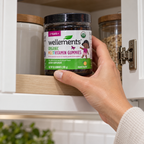 Adult storing a Wellements gummies bottle in an upper cabinet