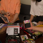 Players examining Who Killed Mia evidence sheets and watching a Mia Star video on a smartphone.