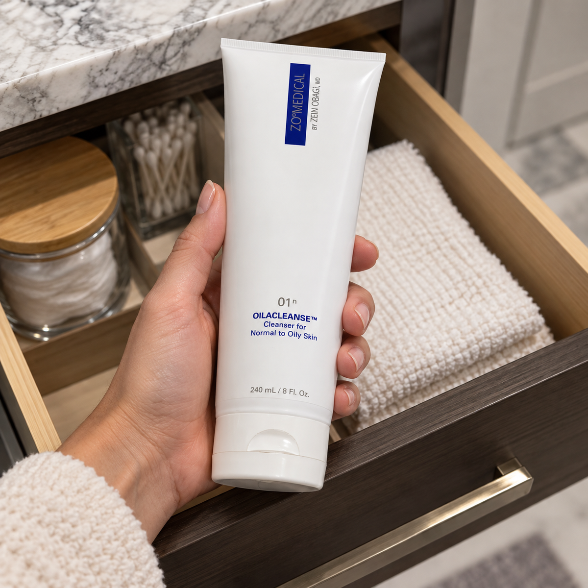 Adult taking ZO Medical Oilacleanse 240 mL from a bathroom drawer
